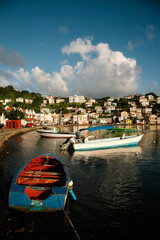 Harbor scene with colorful fishing boats moored close to shore and the port city capital of St Georges in the background on a sunny day; St Georges, Grenada, Caribbean