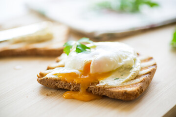 Wall Mural - Fried toast bread with spread and poached egg, on a wooden table.