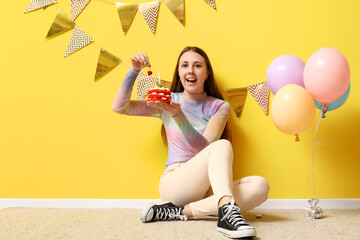 Poster - Beautiful young woman with birthday cake on yellow background