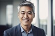 © Baba Images - Middle aged asian businessman smiling and looking at camera in the office portrait