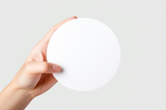 Female hand holding empty circle round shape mockup light background. White template blank frame border surface