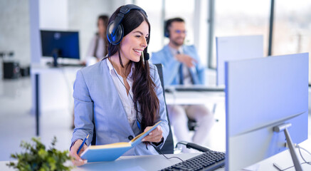 IT service support agent taking notes while talking with customer during online phone call at help desk office.