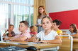 © JackF - Portrait of focused preteen schoolgirl writing exercises in workbook during lesson in classroom ..