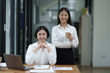 Wall Mural - Portrait of young professional businesswoman working together in the office room, looking at the camera.