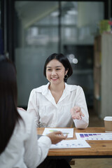 Wall Mural - Beautiful Asian smart businesswoman discussing the project with her coworker, brainstorming the idea for the new projects.