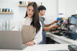 © ijeab - Two young managers or shop owners having some discussion working on a laptop at the counter of the shop or cafe.