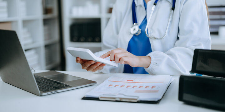 Healthcare costs and fees concept.Hand of smart doctor used a calculator and smartphone, tablet for medical costs at hospital