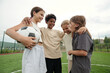 © pressmaster - Four laughing intercultural friends standing in front of each other after game of soccer and having chat while enjoying rest after play