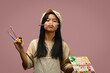 © Prathankarnpap - Adorable teenage girl holding palette and paint brushes on pink background. Art, creativity and education concept
