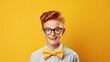 Teenage boy with ginger hair glasses and bow ties isolated on yellow background