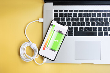 Close-up usb cable connect phone and laptop computer new technology concept on yellow background.