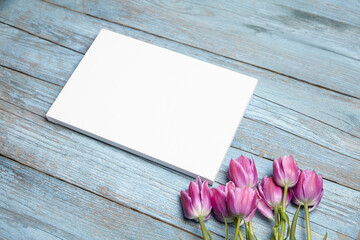 Wall Mural - Blank white canvas mockup with flowers on wood background. Rectangular canvas, blue wood backdrop