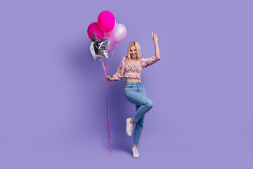 Sticker - Full size portrait of overjoyed cute girl hand hold helium balloons dancing chilling isolated on purple color background