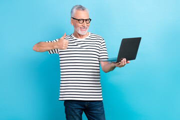 Poster - Photo portrait of nice elderly man showing thumb up netbook good quality dressed stylish striped outfit isolated on blue color background