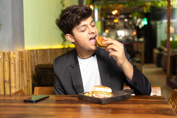 Young indian boy eating food at restaurant