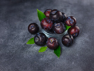 Wall Mural - Sweet plums on dark background. Fresh blue plums with leaves. Food fruit Background. Summer postcard. Harvesting in garden, Harvest of plum