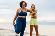 © (JLco) Julia Amaral - Two happy women doing warm-up exercises on the beach