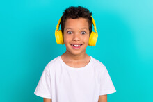 Photo Of Cheerful Small Schoolkid Toothy Smile Enjoy Listen Music Headphones Isolated On Teal Color Background