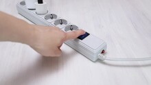 Female Hand Turns Off The Power Button On The Surge Protector Power Strip With Sockets Leaving Home, Fire Safety, Saving Electricity