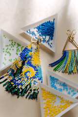 Wall Mural - Triangular bead trays with beaded earrings. Different colored seed beads in containers for needlework and beading. Creativity and  hobby concept