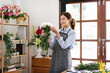 © Katcha - Female florist in apron holding white chrysanthemum with enjoying to creating and designing floral for