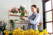© Katcha - Female florist in apron holding white chrysanthemum with enjoying to creating and designing floral for