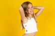© Roquillo - blonde kid girl wearing white T-shirt over yellow studio background stretching arms, relaxed position.