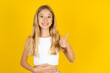 © Roquillo - blonde kid girl wearing white T-shirt over yellow studio background happy positive smile hands on belly show thumb-up fine healthy