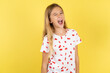 © Roquillo - blonde kid girl wearing polka dot shirt over yellow studio background winking looking at the camera with sexy expression, cheerful and happy face.