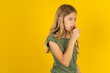 blonde kid girl wearing green T-shirt over yellow studio background feeling unwell and coughing as symptom for cold or bronchitis. Healthcare concept.