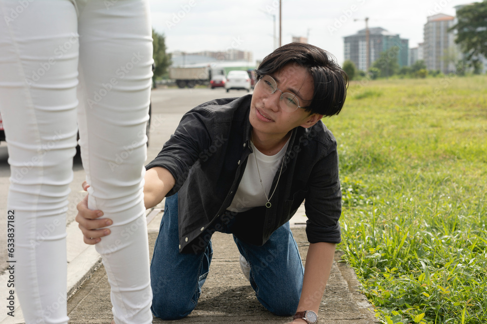 A young man goes down on his knees and grabs the leg of his girlfriend ...