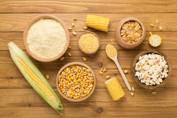 Maize products with fresh corn cobs on wooden background, top view