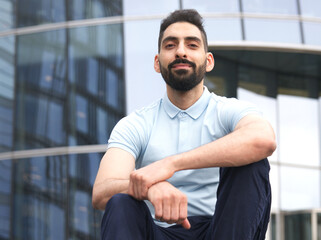 Portrait of Arab Arabian young handsome happy muslim bearded man with beard in casual clothes, islamic person, university or college student or successful businessman outdoors at campus, smiling