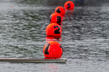 Five lanes at the finish line for a rowing competition. The rowing scull or shell is crossing number one lane for first place in a regatta competition. The lone sleek boat has a white bottom.