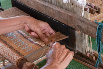 The traditional weaving of handmade cotton on the manual wood loom in Thailand.