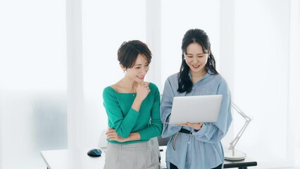Leinwandbilder - オフィスでノートパソコンを見ながら話す二人の女性