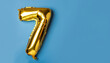 Banner with number 7 golden balloon with copy space. Seven years anniversary celebration concept on a blue background.