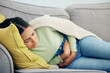 © Tamline L/peopleimages.com - Stomach pain, pms and woman on a sofa with stress, bad or gut health, gas or ibs in her home. Abdomen, anxiety and female person in living room with gas, digestion or constipation from endometriosis