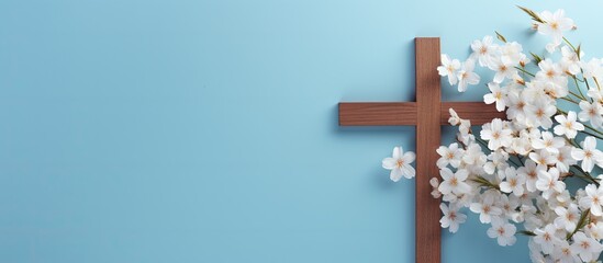 Religious themed flat lay featuring a wooden cross and spring flowers on a blue background