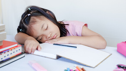 Wall Mural - Portrait Of Cute Little Asian Female Child Sleeping At Desk Tired After Doing School Homework, Exhausted Girl Using Of Books As Pillow, Napping At Table At Home, Closeup Shot, Free Space.