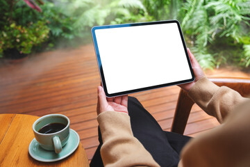 Mockup image of a woman holding digital tablet with blank white desktop screen in the garden