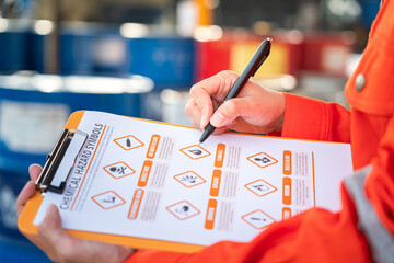 Wall Mural - action of safety officer is using a pen to checking on the hazadous material symbol label form with 