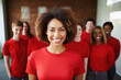 © Maryann - group of people standing in office, confident black woman wearing red leading corporate team with confidence