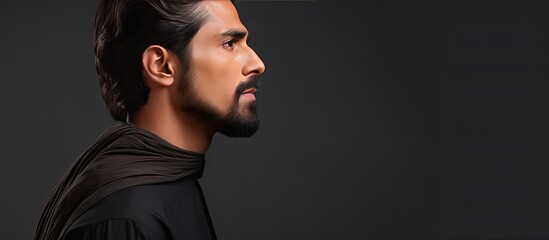 Profile portrait of a young man in traditional Pakistani attire with dark hair mustache and beard against a gray background Horizontal banner with empt
