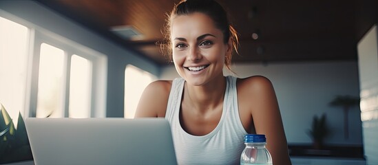 Sticker - Happy sporty woman in workout attire preparing for online training using a laptop and holding a water bottle with space for text