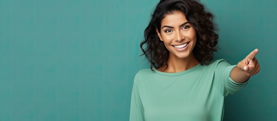 Poster - Smiling cheerful Hispanic woman happily pointing to side and upwards displaying object in empty area