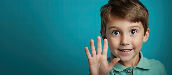 Sticker - Portrait of a five year old boy displaying five fingers on a blue background with empty space