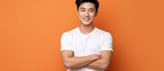 Poster - Happy smiling Asian teenage model in white shirt posing confidently for camera on orange studio background