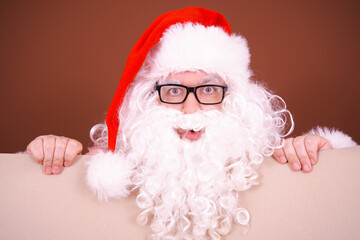 Funny Santa Claus posing with an advertising board on a brown background.