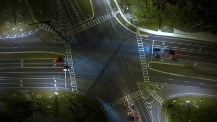Canvas Print - Top view of large multilane road intersection with traffic lights and moving cars and trucks at night. Timelapse of transportation system in USA